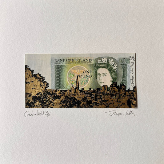 Print of a British pound note on a white card with a wooden surface background